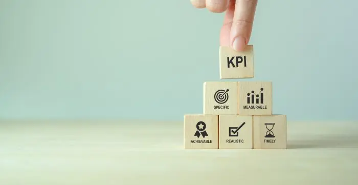 Wooden blocks stacked in a pyramid with KPI on top and Specific, Measurable, Achievable, Realistic and Timely below