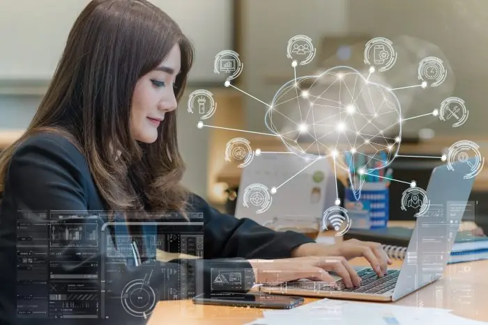 Businesswoman typing on a laptop with glowing AI network and brain graphic overlay