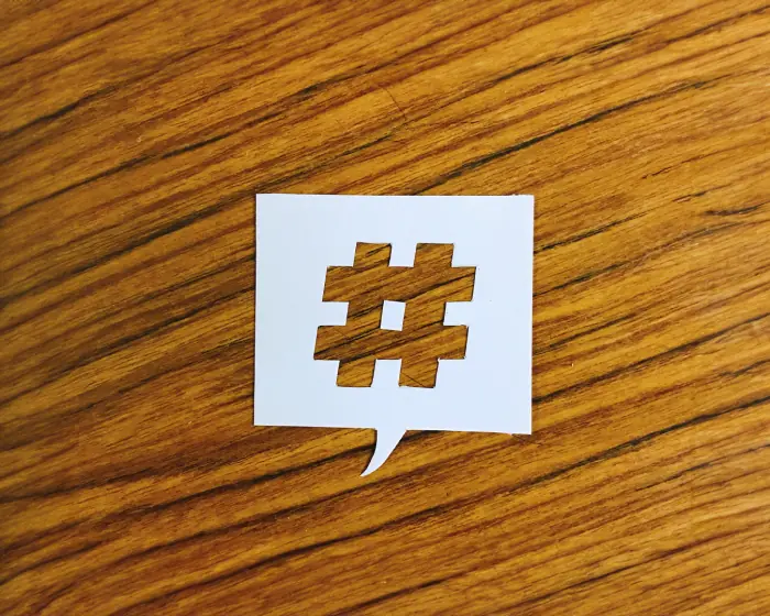 Paper cutout of a hashtag symbol in a speech bubble on a wooden surface