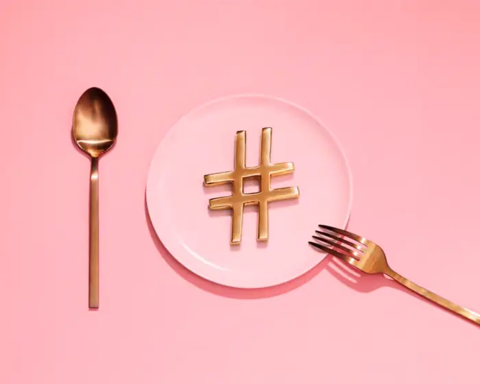 Gold hashtag symbol on a pink plate between a gold spoon and fork